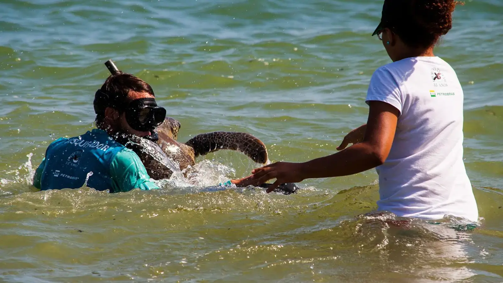 Visitante acompanhado por profissional durante atividade de flutuação na Praia do Sueste