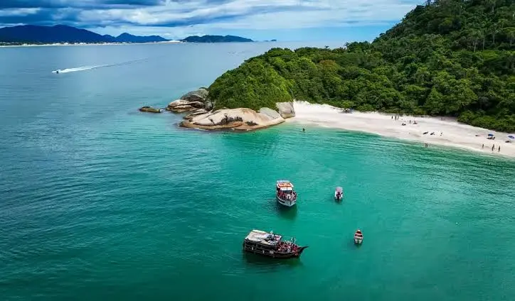 Vista aérea da Ilha do Campeche, com praia, mata e embarcações