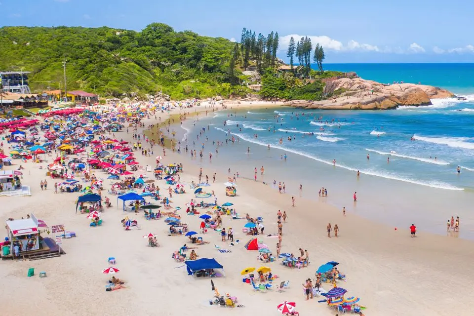 Praia movimentada cercada por vegetação em Florianópolis