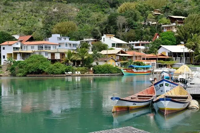 Casas, barcos e águas calmas em uma comunidade costeira de Florianópolis