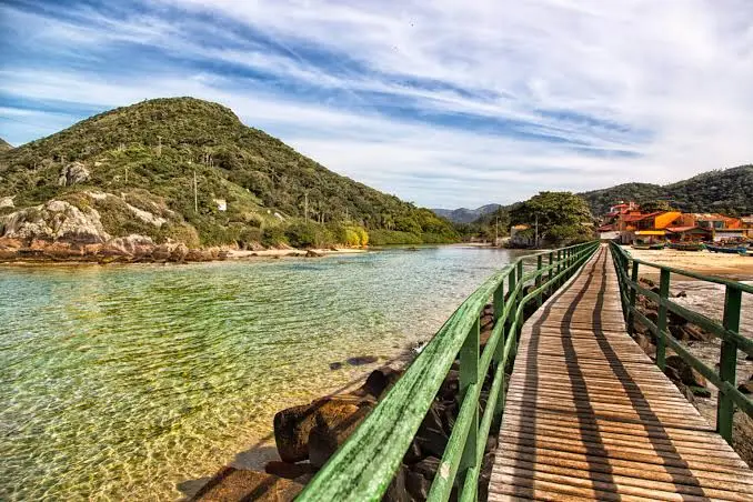 Praia de águas tranquilas com passarela de madeira em Florianópolis