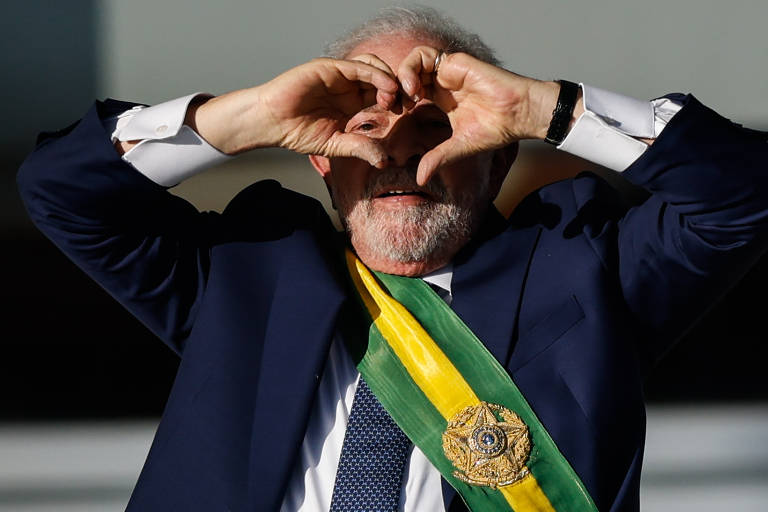 Lula com a faixa presidencial, formando um coração com as mãos, em imagem de arquivo